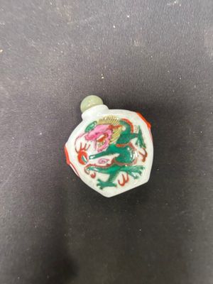 a close up of a small white and green vase with a dragon on it