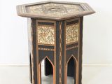 une table d'appoint dont le plateau présente un motif noir et or