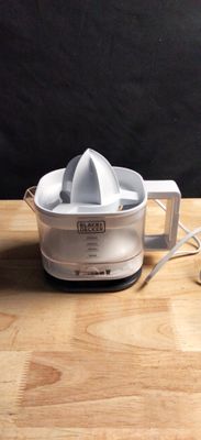 un extracteur de jus blanc posé sur une table en bois, sur fond noir