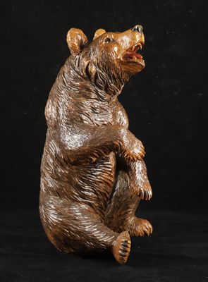 statue d'un ours brun assis sur ses pattes arrière, sur fond noir