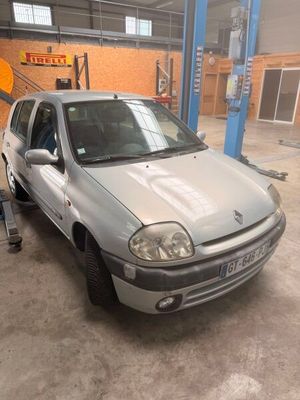 La voiture argentée est garée dans le garage, la porte ouverte.