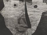 black and white photograph of a man ' s face with boats in the background