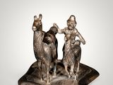 statue of a man and a woman riding a camel on a plate