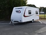 une petite caravane blanche garée sur un parking