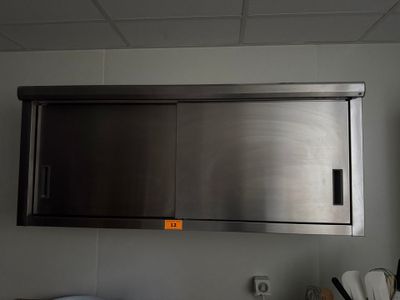 une armoire à pharmacie en acier inoxydable située au-dessus d'un évier dans une cuisine