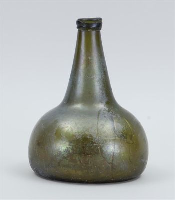 a green glass bottle that is sitting on a table