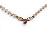 un gros plan sur un collier orné de perles et d'un rubis