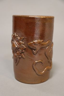 un vase marron orné d'un motif, posé sur une table