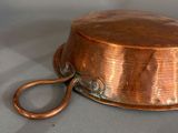 a small copper pot with a handle on a table