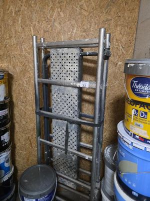 Plusieurs seaux de peinture sont empilés sur un support métallique.