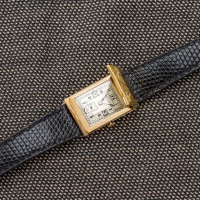 une image représentant une montre dorée et noire sur fond noir