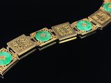a gold bracelet with green stones