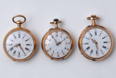 three different types of pocket watches displayed on a white surface