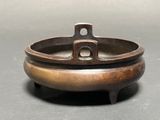 an old bronze incense bowl on a black surface with a gray background