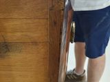a man standing next to a wooden dresser in a store