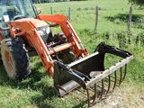 a tractor that is sitting in the grass with a plow attachment