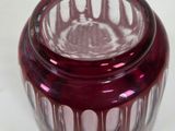a red glass jar with a lid sitting on a table