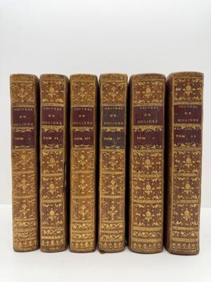 six vieux livres sont alignés sur une surface blanche