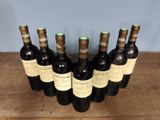 six bottles of wine are lined up in a row on a wooden table
