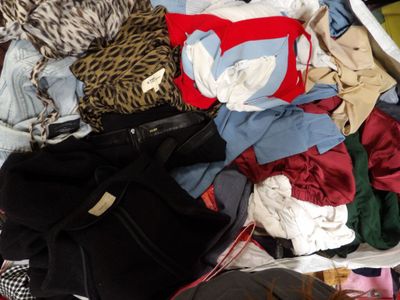une valise remplie de vêtements et un sac à main posés sur un lit