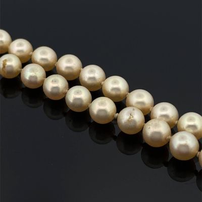 un gros plan sur un collier de perles sur une surface noire