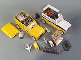 a yellow toy car, a bus, and other toys on a table