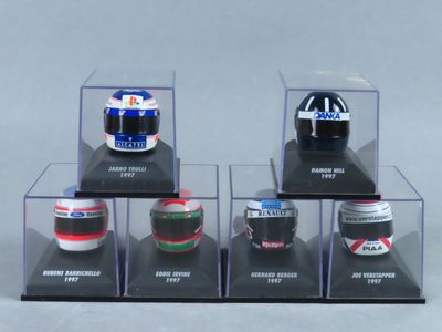 six casques miniatures sont exposés dans une vitrine posée sur un support gris
