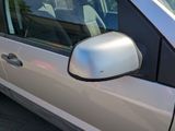 a side view mirror of a silver car in a parking lot
