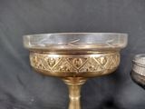 a glass bowl sitting on a pedestal next to a silver bowl