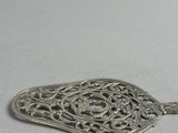 silver plated pendant with filigree design on a white background