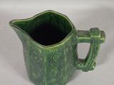 a green pitcher with a handle on a white table
