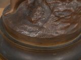 a bronze statue of a woman sitting on a rock