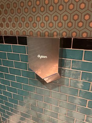 des toilettes dans une salle de bains dont le mur est carrelé de bleu