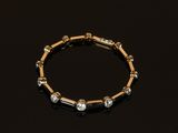 un gros plan d'un bracelet en or et diamants posé sur une surface noire