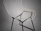 une photo en noir et blanc d'une chaise en fil de fer sur fond gris