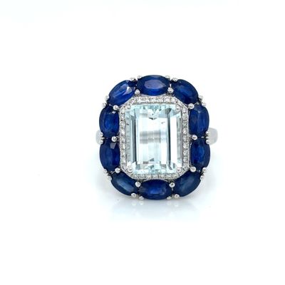 a close up of a ring with an emerald and blue sapphire