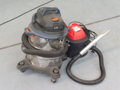 un aspirateur posé par terre à côté d'un bidon