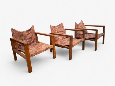 Deux chaises en bois, dotées de coussins à motifs, sont disposées côte à côte sur une surface blanche.