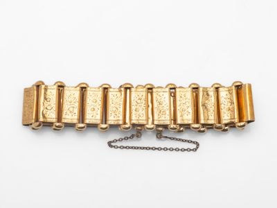 gros plan d'un bracelet en or sur une surface blanche