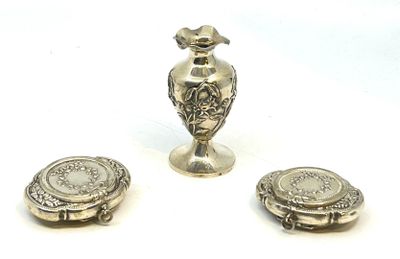 deux vases en argent et une petite assiette en argent posés sur un plan de travail blanc