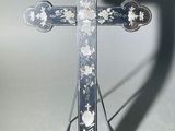 une croix en métal sur laquelle se détache l'ombre d'une personne