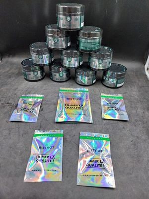 plusieurs sachets de cannabis posés sur une table, à côté d'une pile de cigarettes