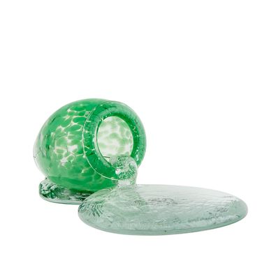 a green glass object sitting on top of a glass plate