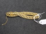 a close up of a gold chain bracelet with a tag on it