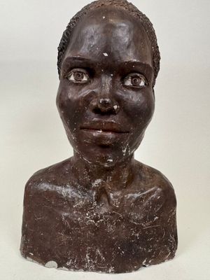 sculpture d'une tête de femme sur une table à fond blanc
