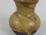 a brown and black vase sitting on a white surface