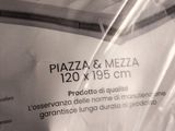 a box of pizzas wrapped in plastic sitting on a bed
