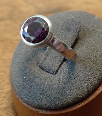 a silver ring with a purple stone on top of it