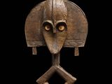 une sculpture en bois représentant une tête d'homme, posée sur un socle