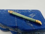 une pierre bleue sur laquelle repose un stylo vert, posée sur une surface blanche